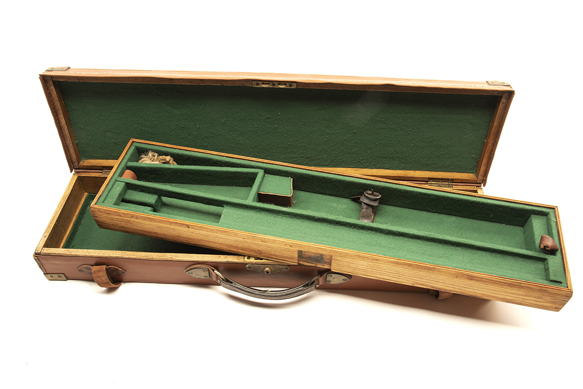 A BRASS-CORNERED OAK AND LEATHER TWO-TIER SINGLE GUNCASE, fitted for 30in. barrels, the interior
