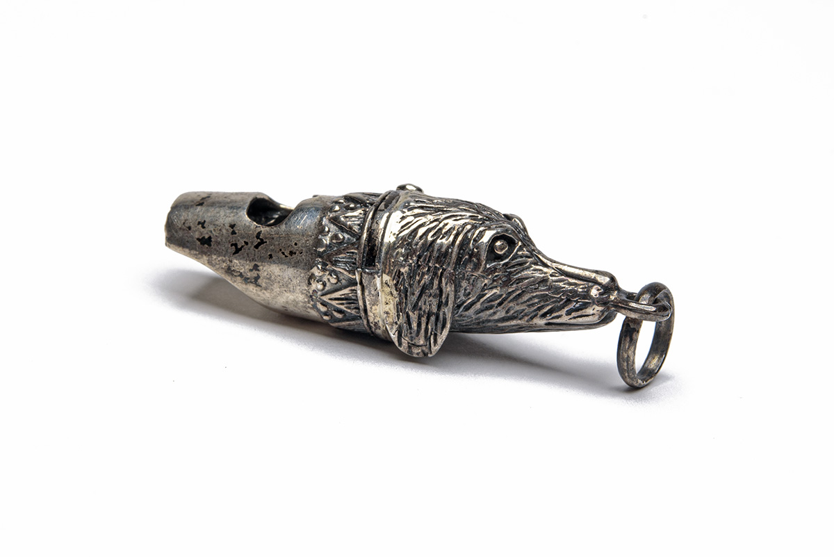 A SILVER DOG WHISTLE, in the form of a retriever head, the nose with lanyard ring, measuring approx.