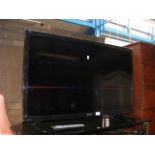 A Sharp flatscreen TV with remote and stand