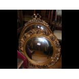 A circular gilt wall mirror together with two othe