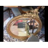 A decorative oval gilt wall mirror