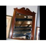 A bevelled wall mirror in mahogany frame with scro
