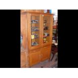 A solid oak display cabinet with two glazed doors,