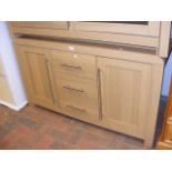An oak effect side cabinet with three central draw