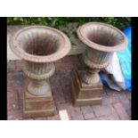 A pair of metal garden urns on stands