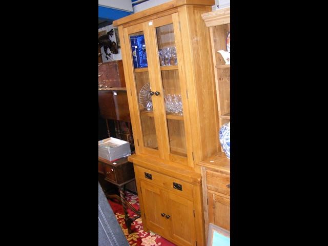 A modern oak glazed bookcase with drawer and cupbo