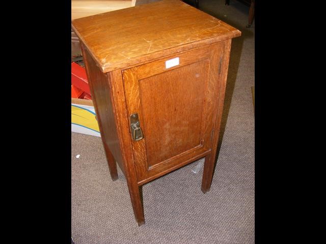 An oak bedside table with swing door to front