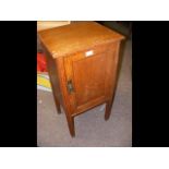 An oak bedside table with swing door to front
