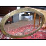 A oval wall mirror with hammered metal frame