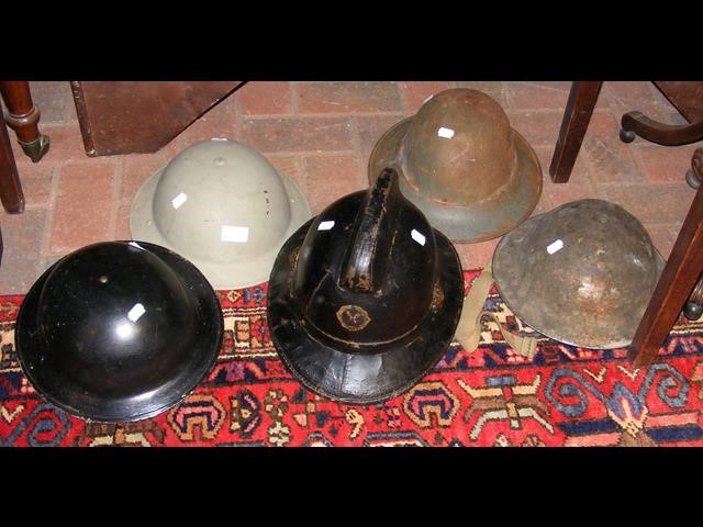 A collection of World War II era helmets, including a Fireman's