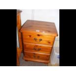 A pine bedside table with three drawers below