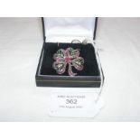 A silver four leaf clover pendant set with rubies