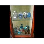 Two shelves of glass paperweights, including Mdina etc