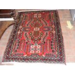 A Persian red ground bordered rug with tree design