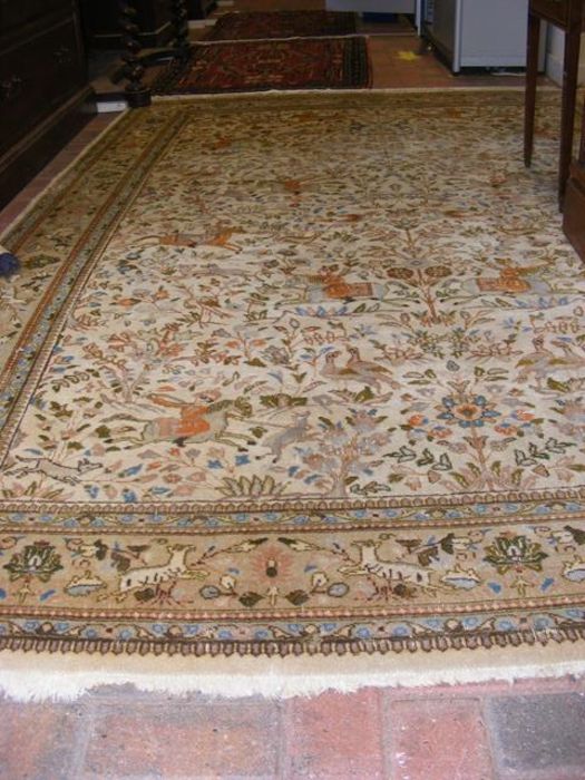 A Persian light ground bordered carpet with huntin