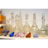 A cluster of cut glass decanters, stoppers and col
