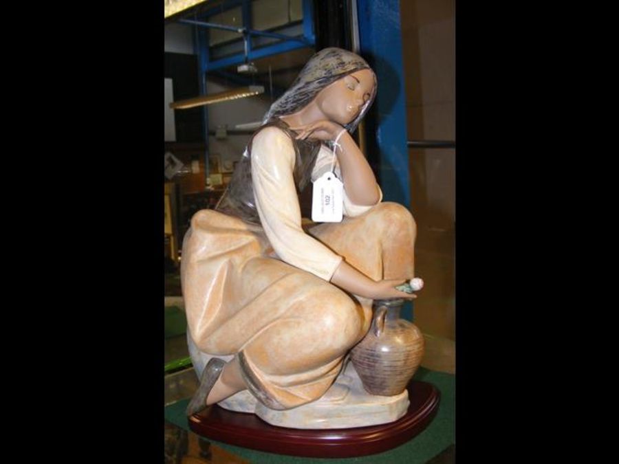 A large Lladro figure of lady holding rose on wood