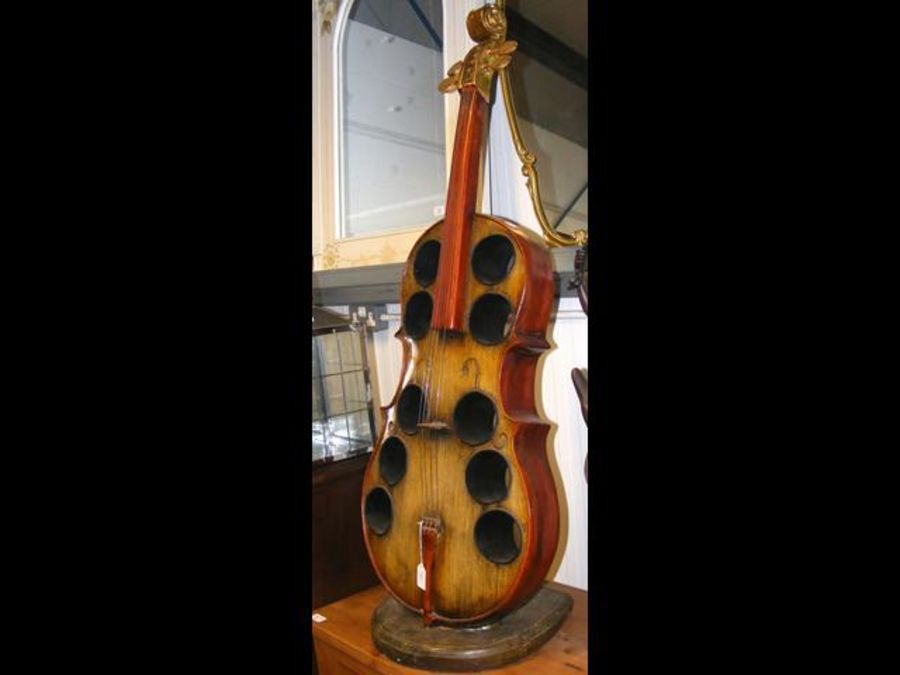 A carved wooden wine stand in the shape of a Cello