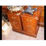 A pair of walnut three drawer bedside chests