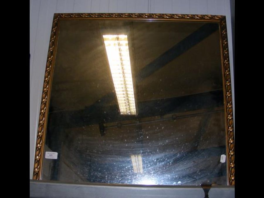 A square wall mirror with leaf detail to frame