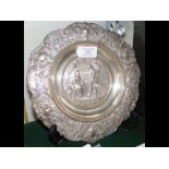 A 23cm diameter silver dish with repousse decorati