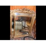 An antique gilt framed cushion mirror 110cm x 85cm