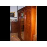 A triple mahogany wardrobe with central mirror to