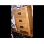 A modern light oak bedside cabinet with three draw