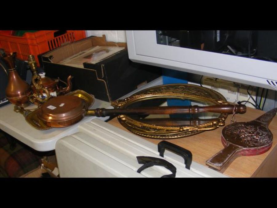 An oval gilt mirror, two embossed brass plaques an