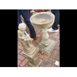 A garden bird bath together with small statue on s