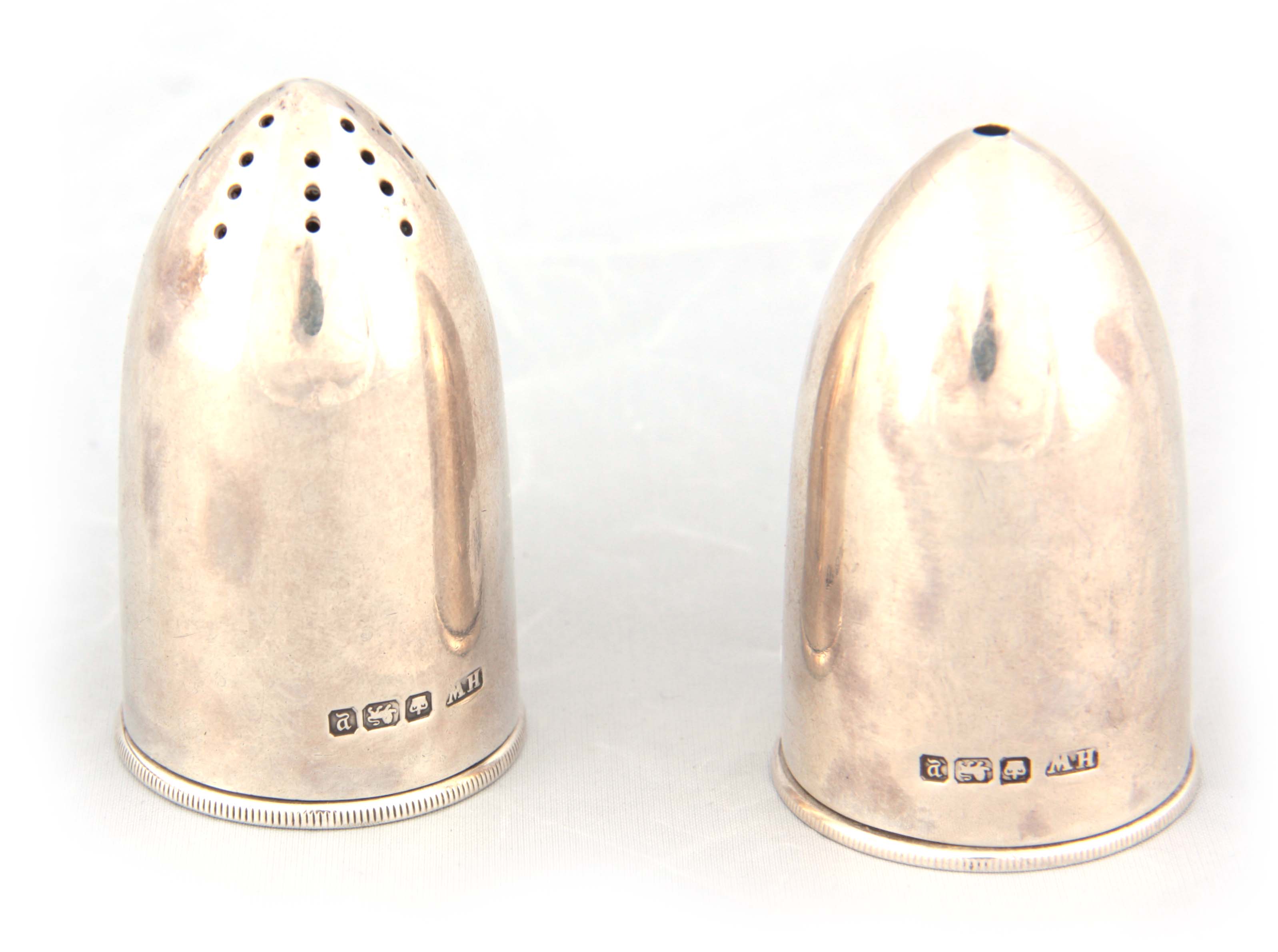 A PAIR OF GEORGE V BULLET SHAPED SILVER SALT AND PEPPER SHAKERS with knurl-edged removable caps