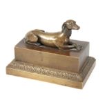 A LATE 19TH CENTURY BRONZE INKWELL depicting a recumbent cast bronze dog, lifting to reveal an