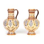 A PAIR OF LATE 19TH CENTURY METTLACH FOOTED BULBOUS EWERS decorated with raised leafwork panels