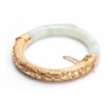 AN ORIENTAL HALF HINGED JADE AND SILVER GILT BANGLE with embossed designs of leafage and flower