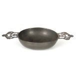 AN 18TH / 19TH CENTURY PEWTER QUAICH of shallow form with shaped cut-out side handles 25cm across