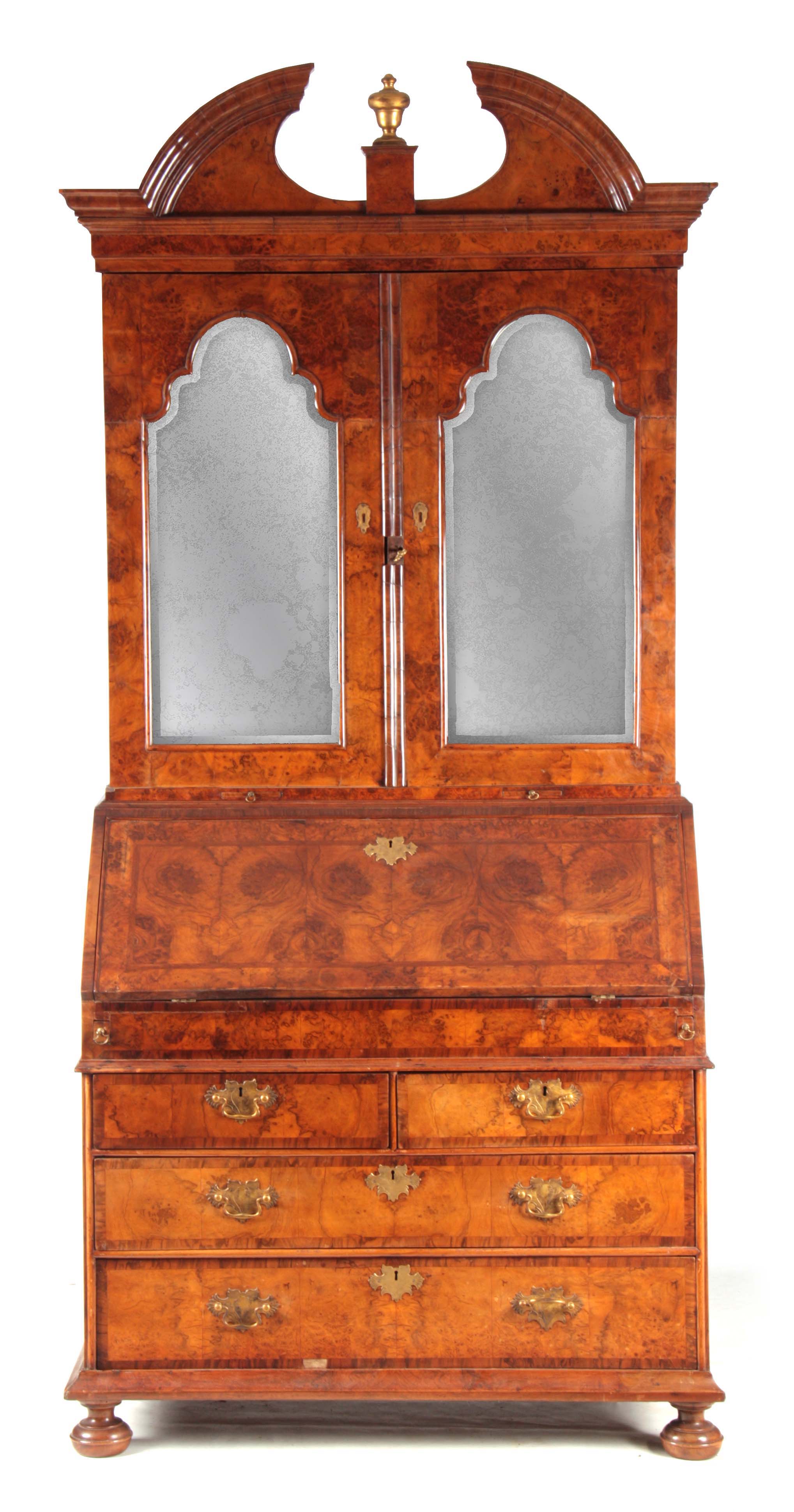 A WILLIAM AND MARY BURR WALNUT BUREAU BOOKCASE with broken arch pediment above shaped mirrored doors