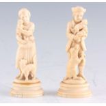 A PAIR OF LATE 19TH CENTURY CARVED IVORY SCULPTURES modelled as husband and wife holding puppies and