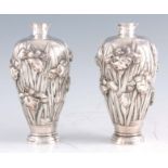 A PAIR OF LATE 19TH CENTURY CHINESE SILVER VASES, the ovoid footed bodies heavily embossed in the