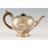 A VICTORIAN SILVER TEAPOT of bulbous form with hardwood handle and finial raised on a circular