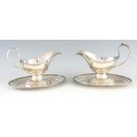A LARGE PAIR OF 19TH CENTURY SILVER PLATED SAUCE BOATS ON FIXED STANDS with feathered borders 25cm