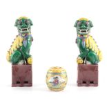 A PAIR OF CHINESE SEATED FOO DOGS ON BROWN PEDESTAL BASES green and yellow glazed highlighted in
