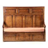 AN EARLY 18TH CENTURY PANELLED OAK BOX SETTLE with high back and open arms, above a box seat with