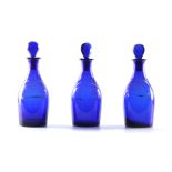 A SET OF THREE EARLY 19TH CENTURY BRISTOL BLUE GLASS DECANTERS for Rum, Brandy and Hollands with