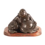 A MEIJI PERIOD JAPANESE PATINATED BRONZE SCULPTURE ON HARDWOOD STAND modelled as a Hotei Buddha