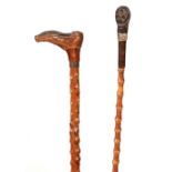 TWO 19TH CENTURY BLACK FOREST CARVED WALKING STICKS one formeds as a boot 95cm overall and smaller.