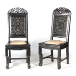 A PAIR OF CHINESE HARDWOOD CHAIRS with carved pierced top rails above carved panelled backs and