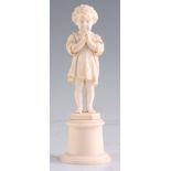 A LATE 19TH CENTURY CARVED IVORY FIGURE modelled as a young boy wearing a robe and crucifix standing