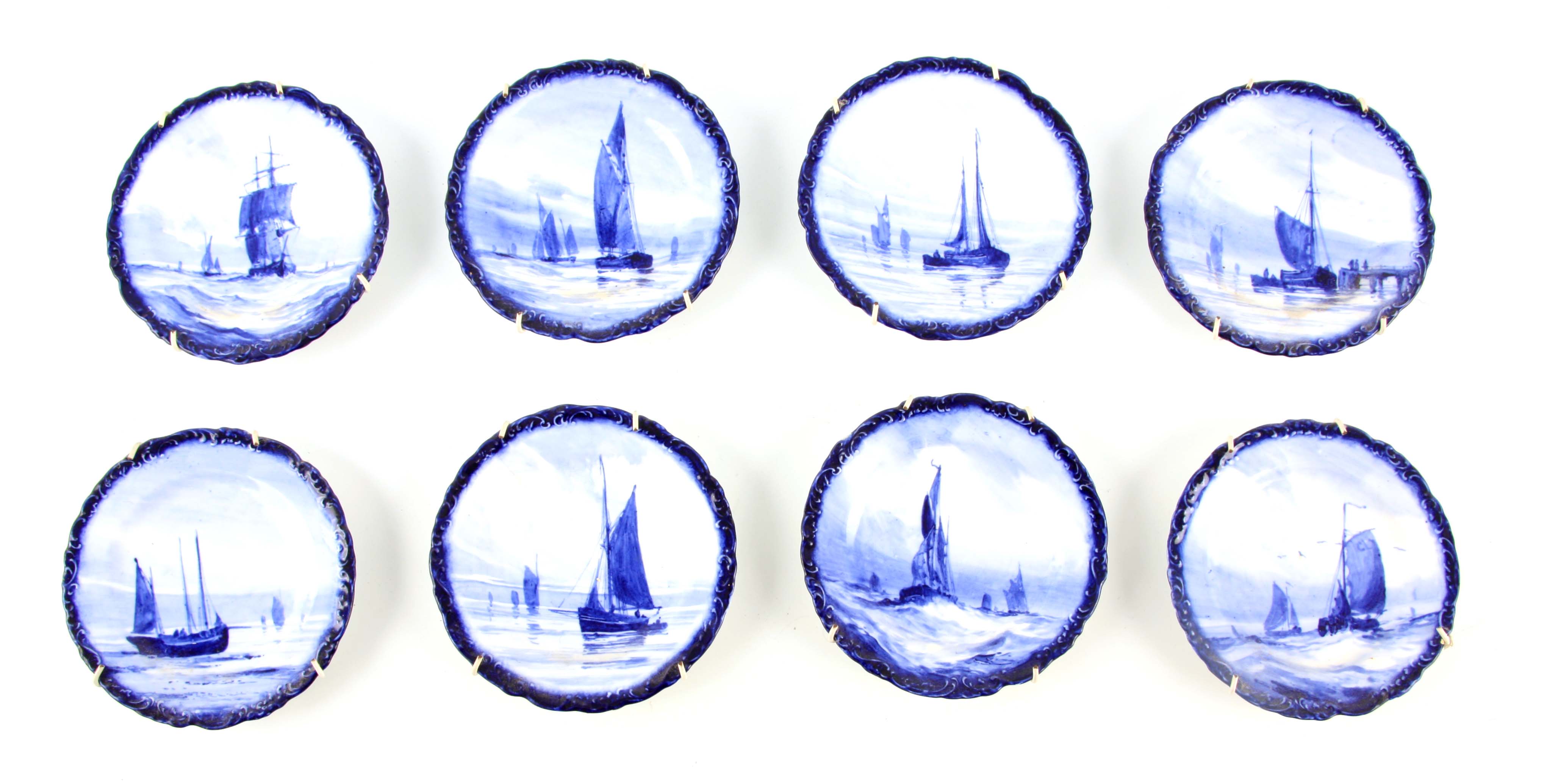 A SET OF EIGHT ROYAL CROWN DERBY SMALL HANGING PLATES painted with differing sailboats on a blue