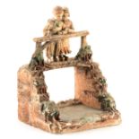 A 19TH CENTURY TERRACOTTA FIGURE GROUP depicting two children on a bridge - the back impressed LMC