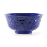 A CHINESE BLUE GLAZED BOWL having relief work chasing five claw dragons to the side, signed with six